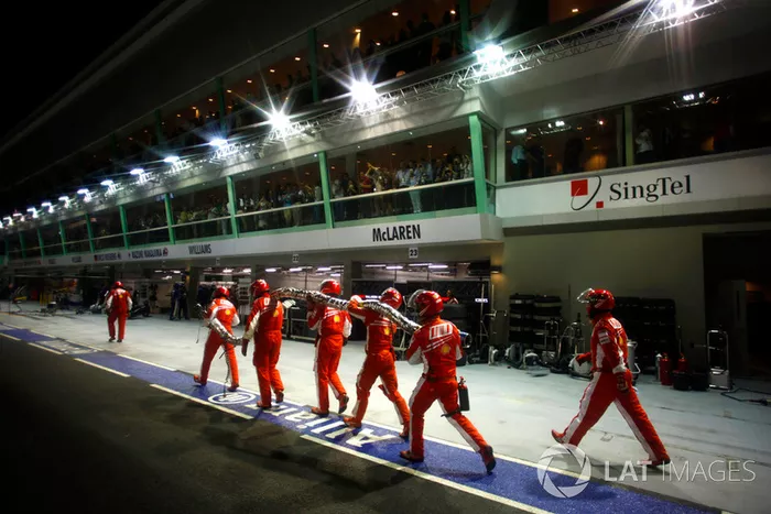 Les mécaniciens Ferrari ramènent le tuyau de ravitaillement en essence au garage