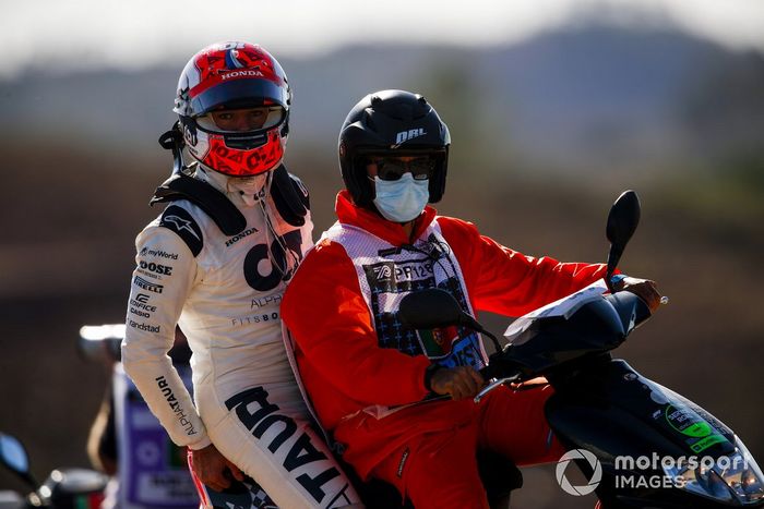 Pierre Gasly, AlphaTauri es llevado por un oficial en un scooter