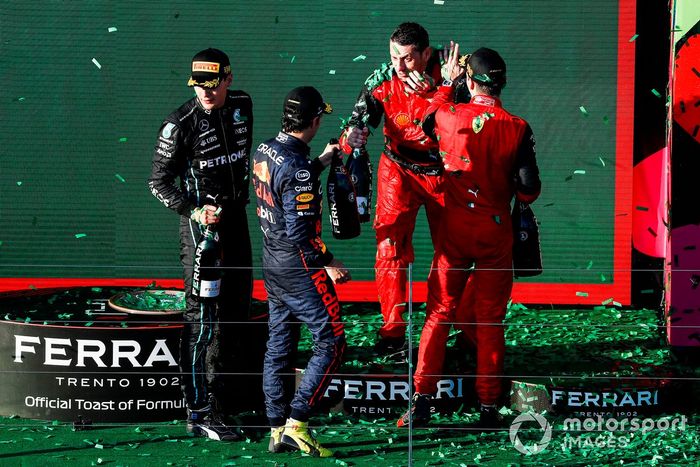 Sergio Pérez, Red Bull Racing, segundo, Charles Leclerc, Ferrari, primero, George Russell, Mercedes-AMG, tercero, y el representante de Ferrari celebran en el podio