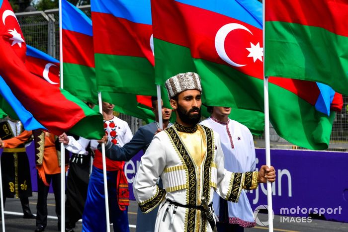 Artistas con trajes tradicionales con banderas de Azerbaiyán en la parrilla
