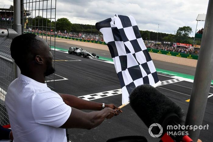 Il rapper Stormzy sventola la bandiera a scacchi, mentre Lewis Hamilton, Mercedes AMG F1 W10, taglia il traguardo