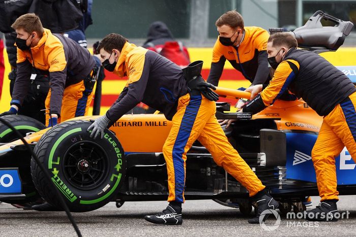 Los mecánicos empujan el coche de Lando Norris, McLaren MCL35M, en la parrilla de salida