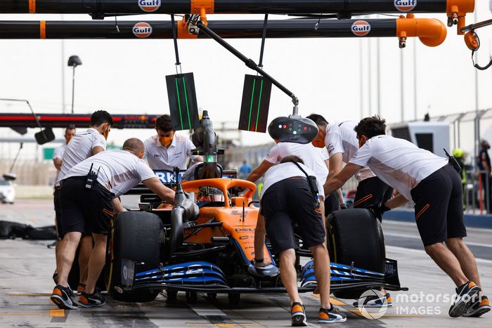 Los mecánicos empujan el coche de Lando Norris, McLaren MCL35M, en los boxes
