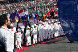 Drivers and grid kids observe the National Anthem on the grid