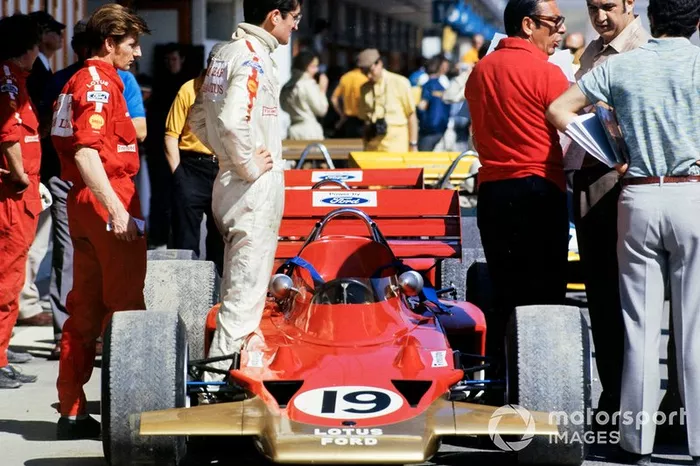 John Miles stands beside his Lotus 72 Ford in the pit lane