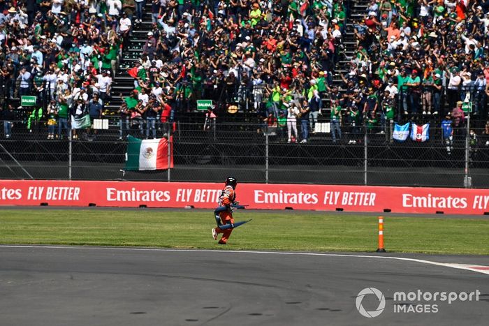 Un oficial de pista recoge las carrocerías rotas del circuito
