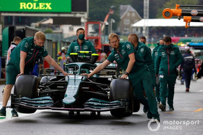 Los mecánicos mueven el coche de Sebastian Vettel, Aston Martin AMR21, en el pit lane