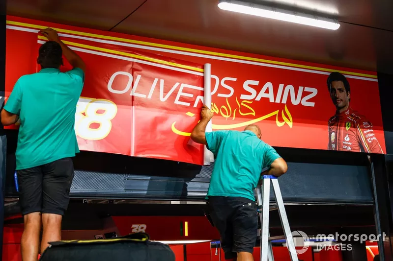 Le personnel du circuit remplace la bannière du garage de Carlos Sainz, Scuderia Ferrari, par celle d'Oliver Bearman, Scuderia Ferrari.
