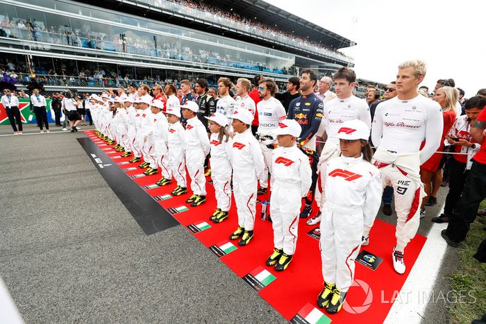 Chicos de la parrilla y pilotos escuchan el himno