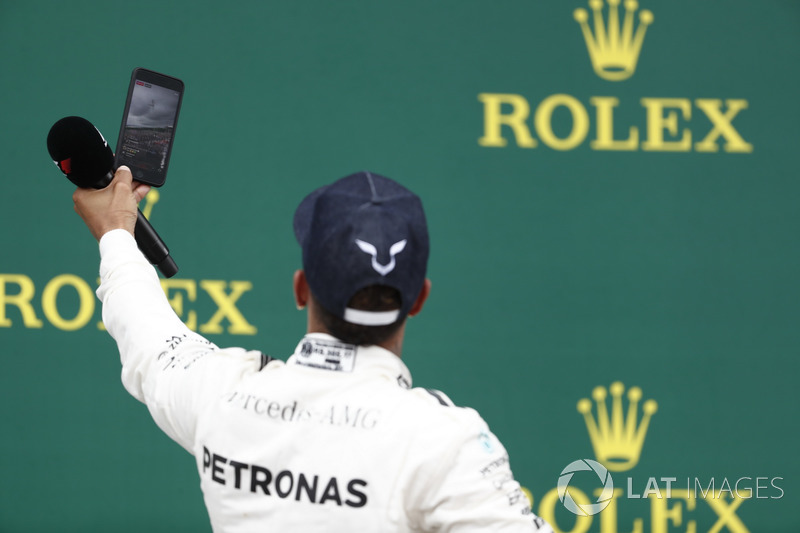Podium: Race winner Lewis Hamilton, Mercedes AMG F1, takes a photo, the crowd in the background