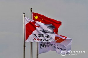 Una bandera china junto a una bandera de Fórmula 1 de la FIA y una bandera de evento de Juss.