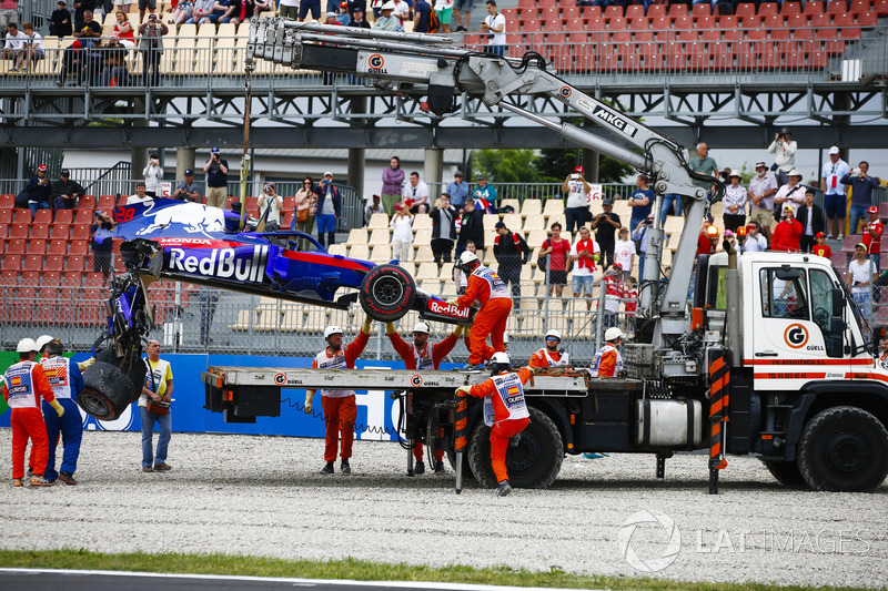 Marshals remove the damaged car of Brendon Hartley, Toro Rosso STR13, from the circuit as the gearbox hangs off the back