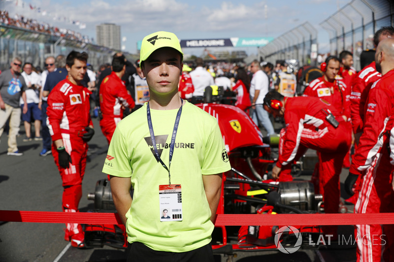 A Grid Kid stands in front of a Ferrari