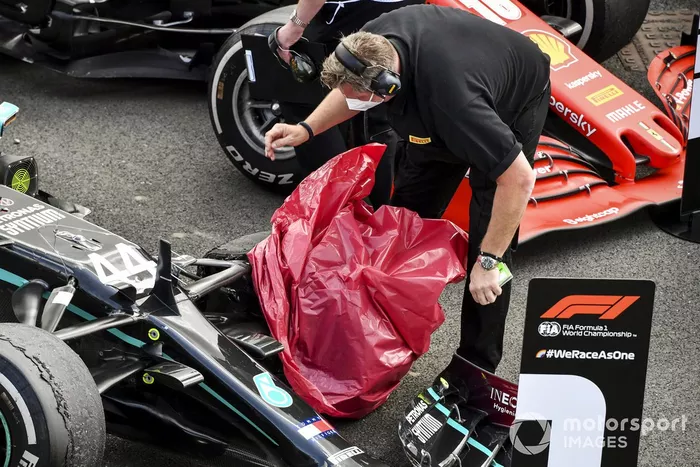 Un técnico de Pirelli cubre el neumático pinchado de Lewis Hamilton, Mercedes F1 W11, en el Parc Ferme
