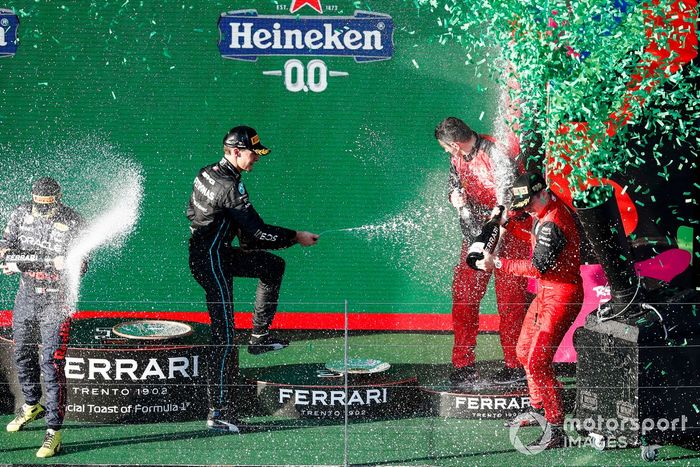 Sergio Pérez, Red Bull Racing, segundo, Charles Leclerc, Ferrari, primero, George Russell, Mercedes-AMG, tercero, y el representante de Ferrari celebran en el podio