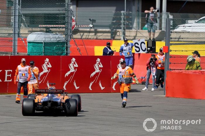 Los oficiales recuperan el coche de Carlos Sainz Jr, McLaren MCL34, después de retirarse con un problema técnico