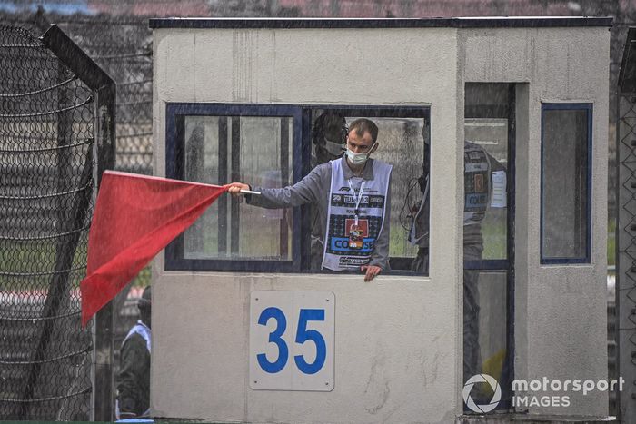 Un oficial de pista agita una bandera roja
