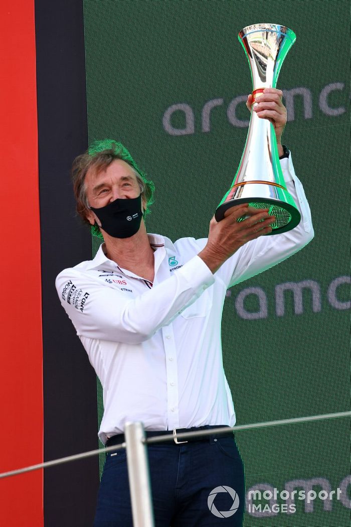 El encargado de Mercedes de recoger el trofeo levanta el trofeo de constructores