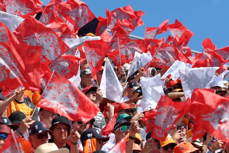 Les supporters agitent des drapeaux rouges et blancs dans les tribunes.