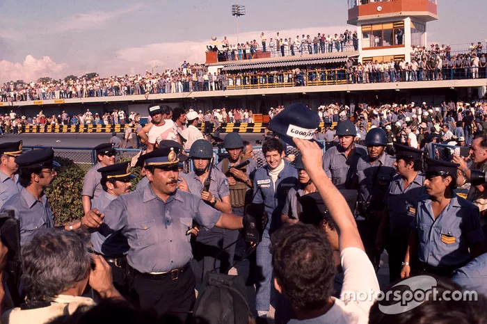 Yarış galibi Jody Scheckter, Wolf Ford ve güvenlik görevlileri