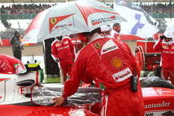 Un mecánico de Ferrari mantener la lluvia fuera de cabina