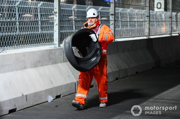 Un comisario recupera un neumático tras el accidente de Franco Colapinto, Williams FW46