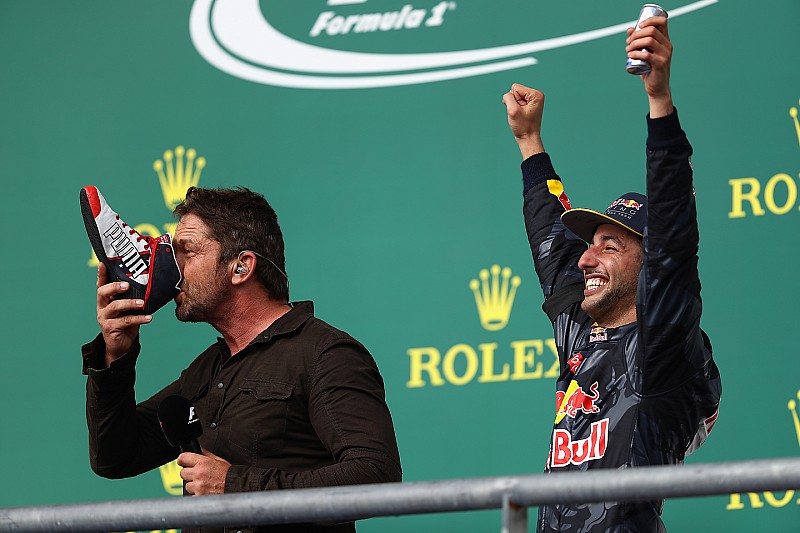 Podio: el actor Gerard Butler toma de la bota del tercer lugar Daniel Ricciardo, Red Bull Racing