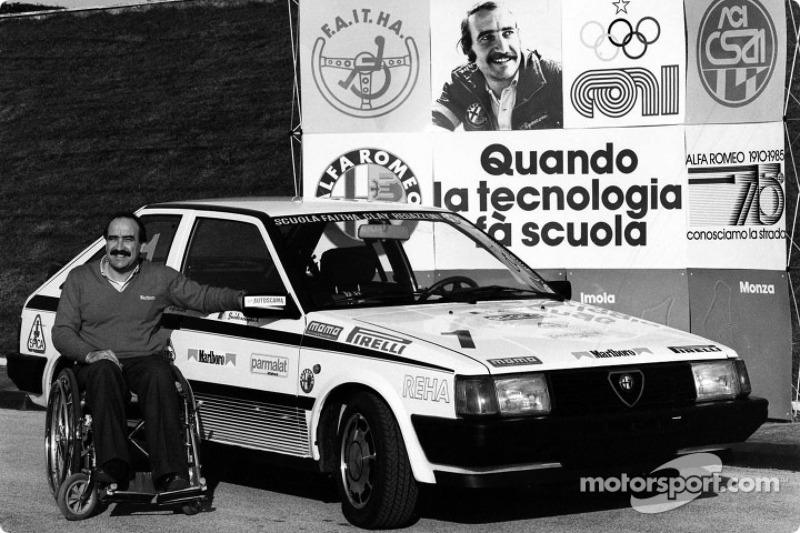 Clay Regazzoni dans une chaise roulante à côté de son Alfa Romeo sponsorée de l'école de conduite pour personnes handicapées à Vallelunga