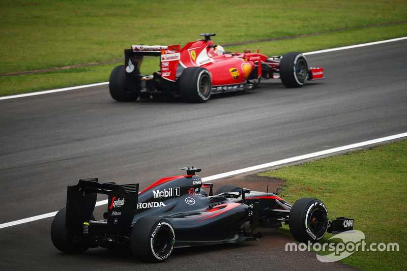 El McLaren MP4-30 de Fernando Alonso, McLaren pasa por Sebastian Vettel, Ferrari en la segunda sesión de práctica